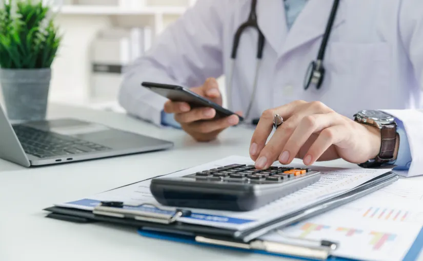 A doctor reviewing their finances with a calculator at a desk